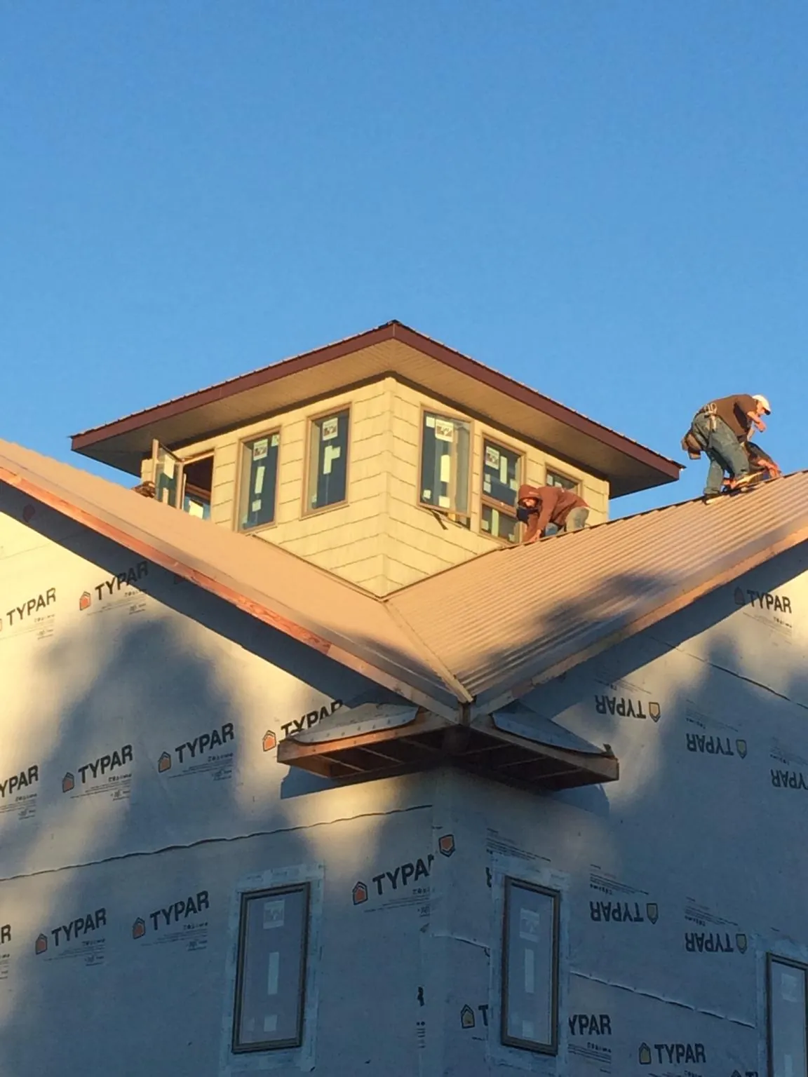 Roofers working around a rooftop cupola on a new metal roof at sunset — Roof Waterproofing in Custer by Roofing Brothers